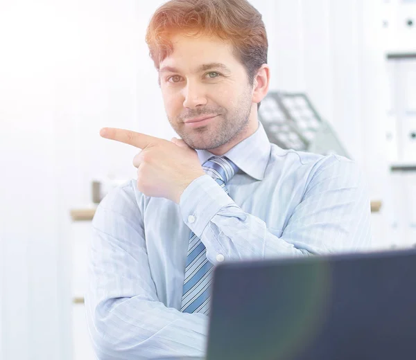 Stilig affärsman sitter bakom ett skrivbord och pekar kopiera utrymme — Stockfoto