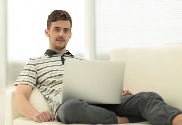 Ευτυχισμένος άνθρωπος με laptop κάθεται στον καναπέ — Φωτογραφία Αρχείου