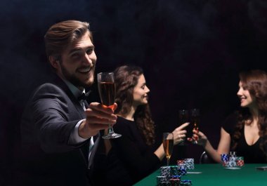 Başarılı bir poker oyununu kutlayan mutlu bir grup insan.