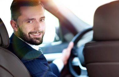 bir araba direksiyon başında oturan ve kameraya bakarak işadamı