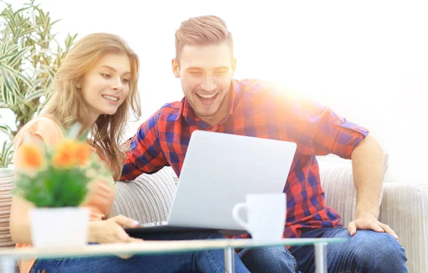 Gelukkige jonge paar kijken naar een favoriete film zittend in een moderne woonkamer. — Stockfoto