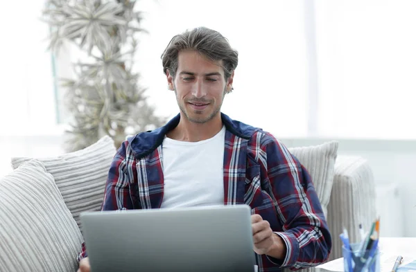 Feliz joven exitoso mirando a la computadora portátil en casa . —  Fotos de Stock