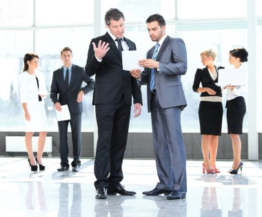 çalışanların çalışma kağıt ayakta ofisinin lobisinde tartışmak.