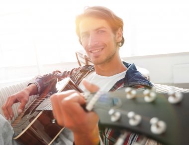gitar oturma odasında kanepede oturan adam. bir yaşam tarzı kavramı