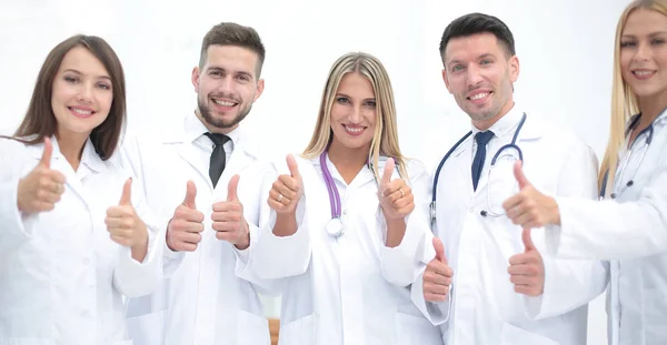 Portrét lékaře a lékařský tým ukazuje palec — Stock fotografie
