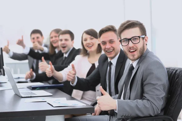 Equipo de negocios con los pulgares hacia arriba mientras está sentado en su escritorio — Foto de Stock