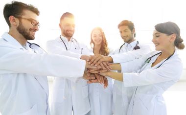 Doktorlar ve hemşireler tıbbi bir ekipte el ele tutuşuyorlar.