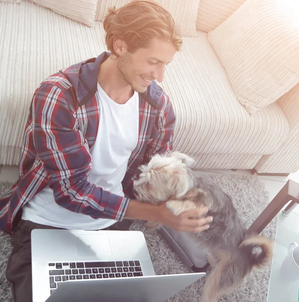 Giovane uomo moderno che gioca con il suo cane in un ampio soggiorno — Foto Stock
