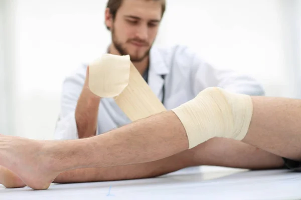 Doctor bandaging a wound on the leg of the patient — Stock Photo, Image