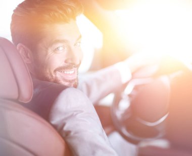 Başarılı bir adam prestijli bir arabanın direksiyonunda oturuyor.