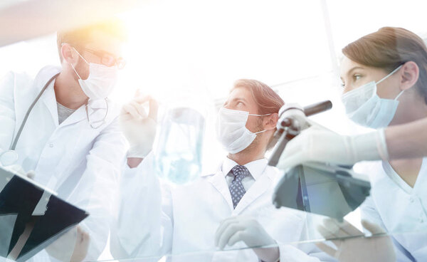 молодые ученые, работающие с микроскопом и пробирками
