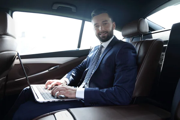 Junge Geschäftsfrau arbeitet an ihrem Laptop, während sie im Auto sitzt — Stockfoto