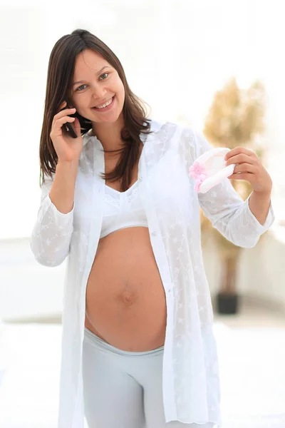 Усміхнена вагітна жінка говорить на своєму смартфоні . — стокове фото