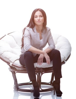 Genç kadın bir yuvarlak rahat yumuşak büyük sandalyede oturuyor.