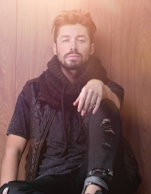 Tuğla duvarın yanında oturan yakışıklı olgun adam. Erkek modası.