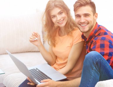 Dizüstü bilgisayarı olan iki öğrenci kanepede oturuyor.