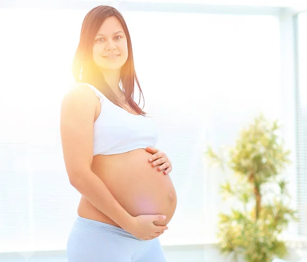 Portrait of young pregnant woman on a light background. — Stock Photo, Image