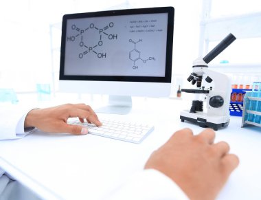 A scientist uses a computer and a microscope clipart