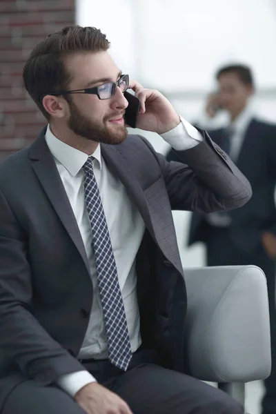 Charmig affärsman talar i telefon i en modern byggnad — Stockfoto