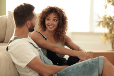 Yeni evliler yeni bir dairede kanepede oturuyor..