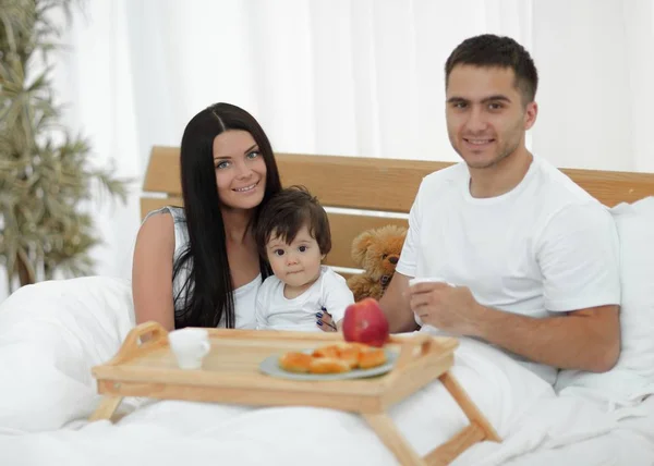 Familia desayunando en la cama en casa — Foto de Stock