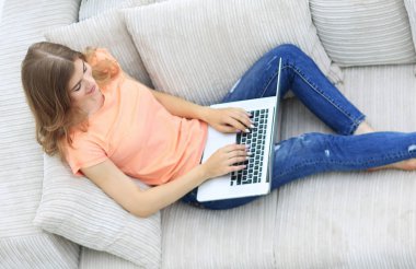 kız öğrenci dizüstü bilgisayar kanepede döşenmesi ile çalışma.