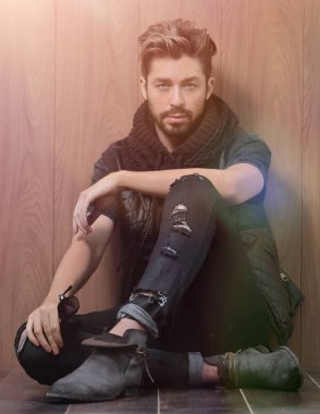 Sıradan giyinmiş sakallı bir adam oturur.