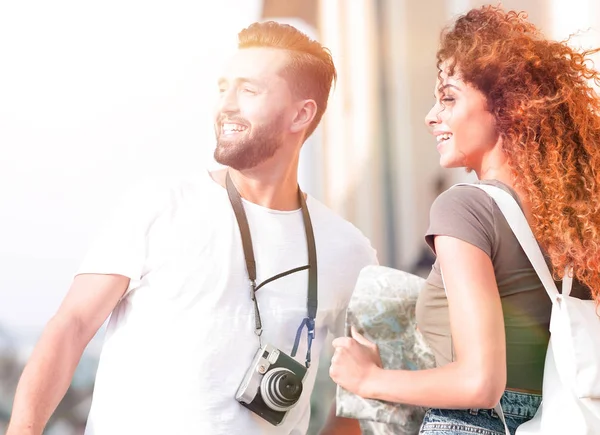 Casal jovem andando e olhando para um guia enquanto parece feliz — Fotografia de Stock