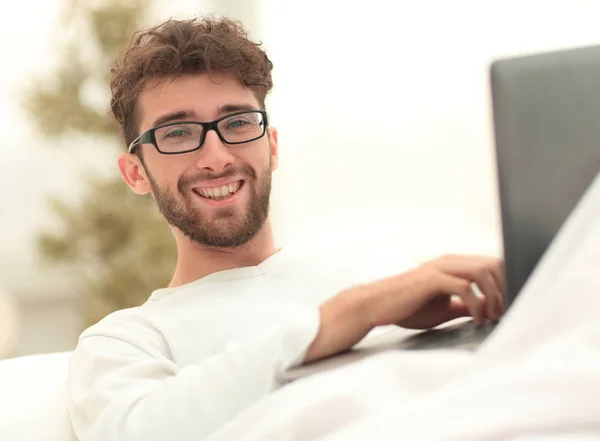 Sorrindo homem usando laptop deitado na cama — Fotografia de Stock