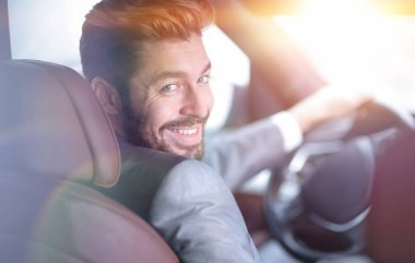 Başarılı bir adam prestijli bir arabanın direksiyonunda oturuyor.