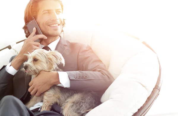 successful businessman holds his dog and pet and talks on the sm