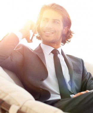 iş adamı rahat bir sandalyede otururken Smartphone'da konuşuyor.