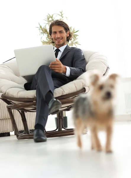 Jeune homme d'affaires avec ordinateur portable assis dans un grand fauteuil confortable . — Photo