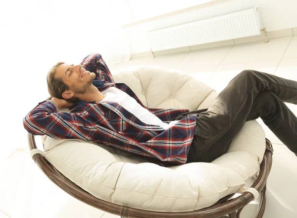 Hombre moderno está descansando sentado en una silla cómoda grande. vista lateral . —  Fotos de Stock