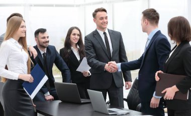 Ofisteki bir toplantıda iş ortakları tokalaşıyor.