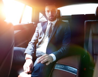 Bir arabanın arka koltuğunda oturan başarılı iş adamı