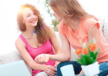 İki genç kadın kahve masasında konuşuyor ve oturuyor.