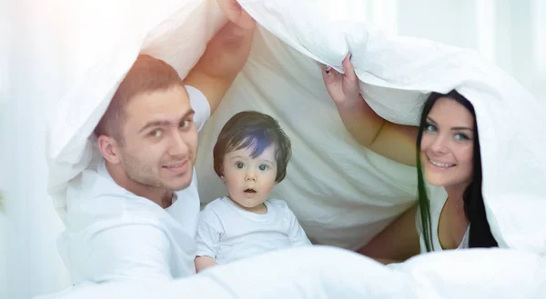 Gezinnen met kinderen in bed onder een deken — Stockfoto