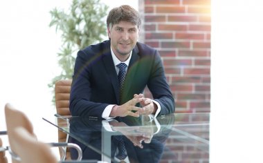 Bir boş konferans salonunda bir masada oturan proje yöneticisi