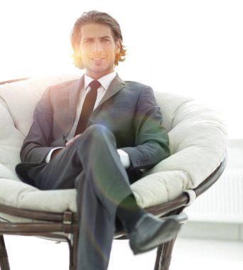 Kendine güvenen işadamı büyük bir rahat sandalyede oturuyor.
