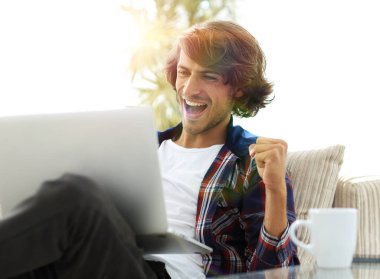 bir sehpa oturan bir dizüstü bilgisayar ile çok mutlu adam.