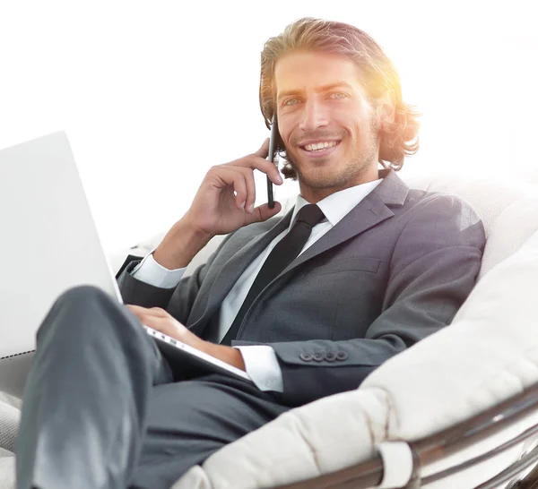 Hombre de negocios hablando en el teléfono inteligente sentado en silla en su casa —  Fotos de Stock