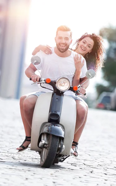 Счастливая молодая пара катается на скутере по городу в солнечный день — стоковое фото