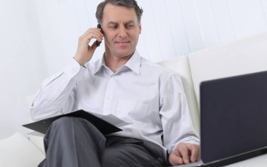 laptop ile çalışan ve bir cep telefonuyla konuşan işadamı