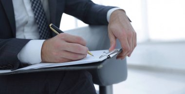 İşadamı bir sözleşme imzalar. Elinde kalem tutan.