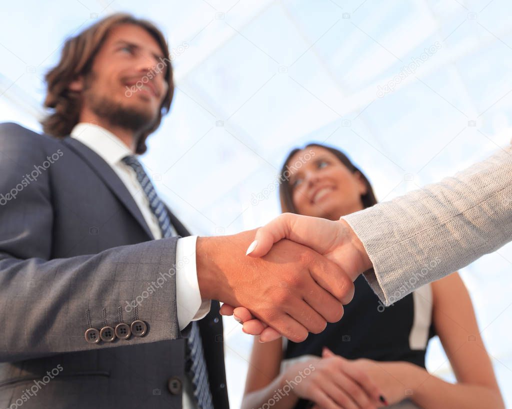 Businesspeople  shaking hands against room with large window loo