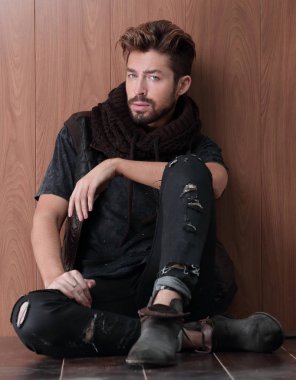 Tuğla duvarın yanında oturan yakışıklı olgun adam. Erkek modası.