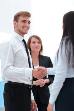 onun ortağı ile tokalaşırken komik gülümseyen iş adamı.