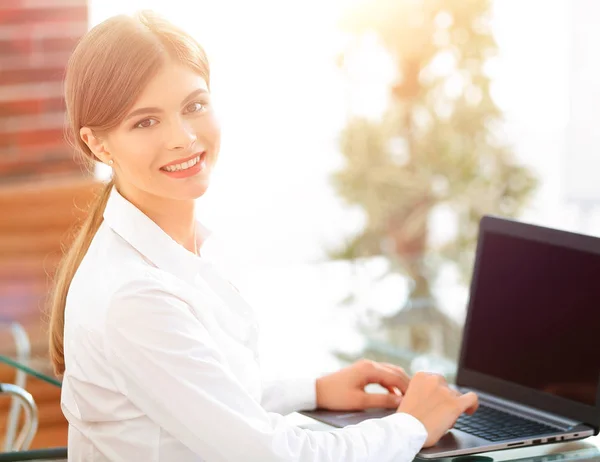 Jovem mulher de negócios sentada em sua mesa em um escritório, trabalhando em um computador portátil — Fotografia de Stock