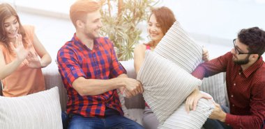 yastık savaşı oynarken, kanepede oturan neşeli arkadaşları